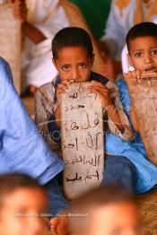 Image du Maroc Professionnelle de  Sous une tente on découvre la méthode traditionnelle de l’enseignement et l’apprentissage du saint coran prodigués aux enfants. Les jeunes récitent les sourates devant le Fkih (instituteur) qui écoute attentivement les versets ainsi récités, Samedi 18 septembre 2006, aux environ de Tan Tan dans un site désertique sur lequel la ville, a toujours accueilli la majorité des tribus et des grandes familles nomades du désert lors d'un grand Moussem, danses chants, course de chameaux et fantasia font partie des festivités. (Photo / Abdeljalil Bounhar)

